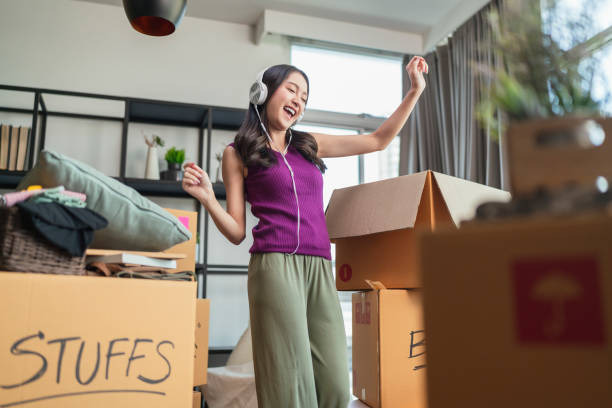 a woman with headphones on dancing to the music as she moves her stuff in boxes
