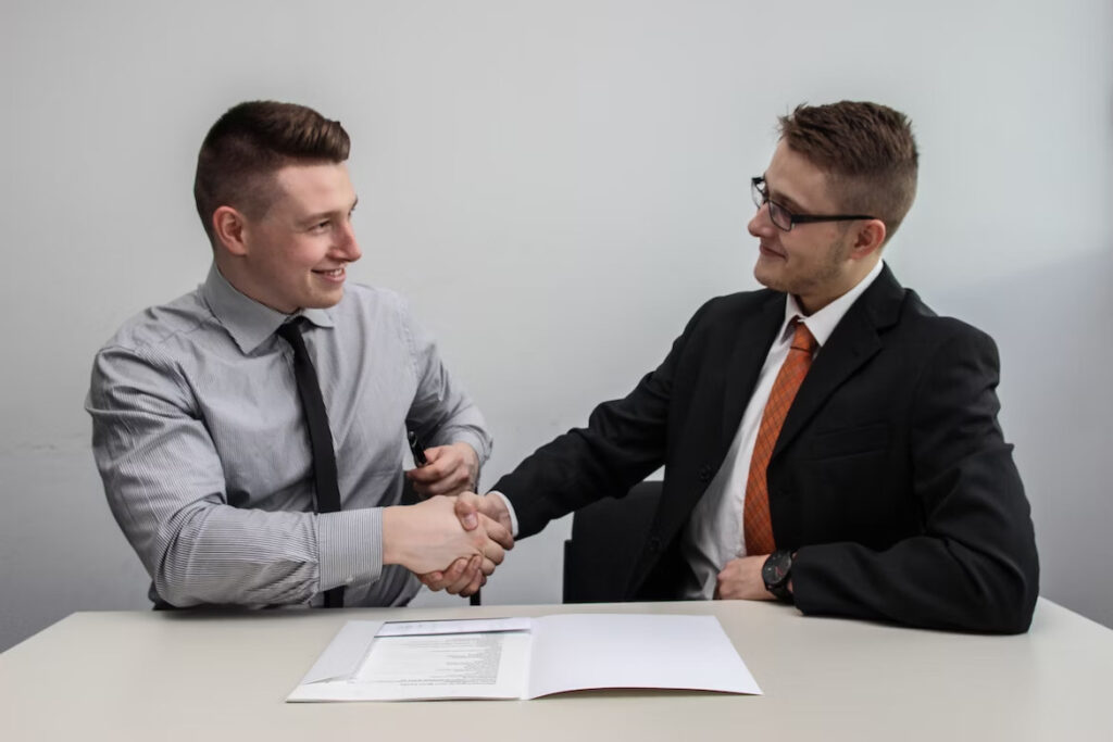 two men in suit shaking hands while smiling