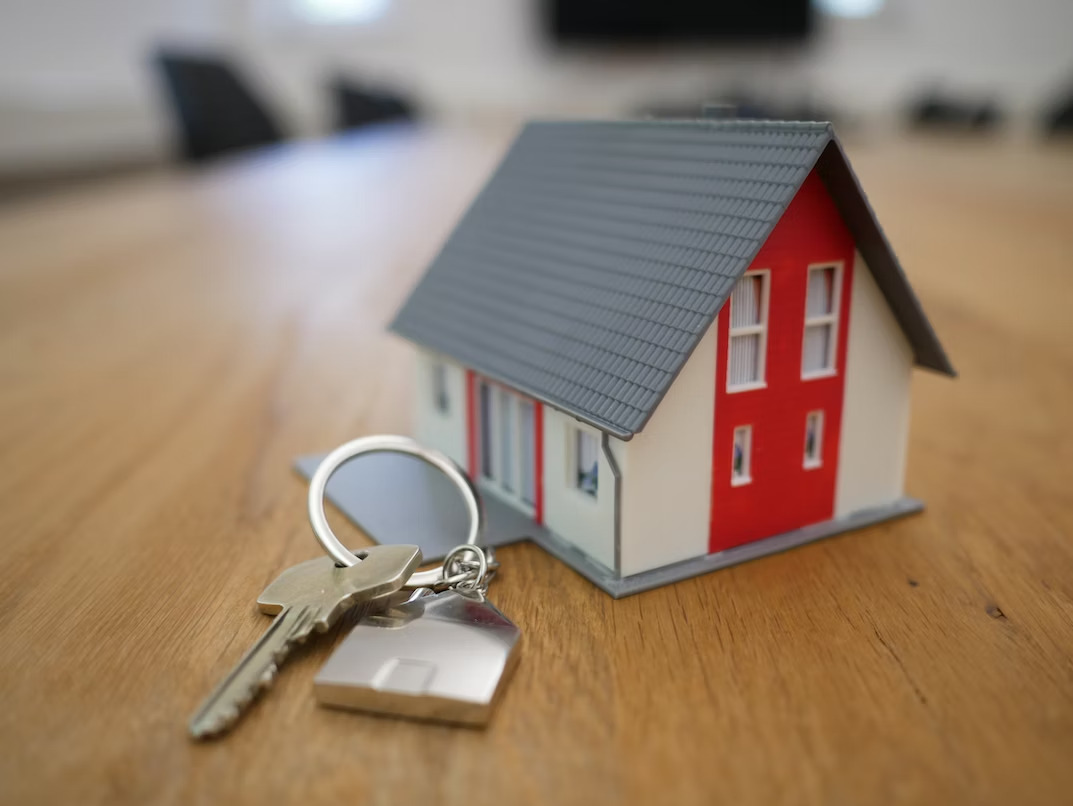 a miniature house with keys beside it on a table
