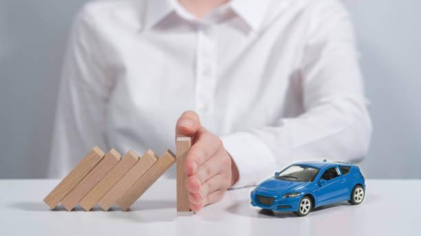 a hand stopping dominoes falling from a blue car