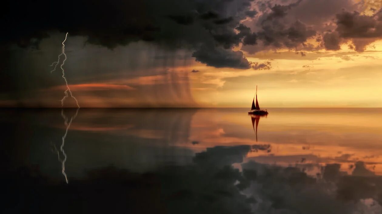 silhouette of a boat in the middle of ocean with an incoming storm during the sunset