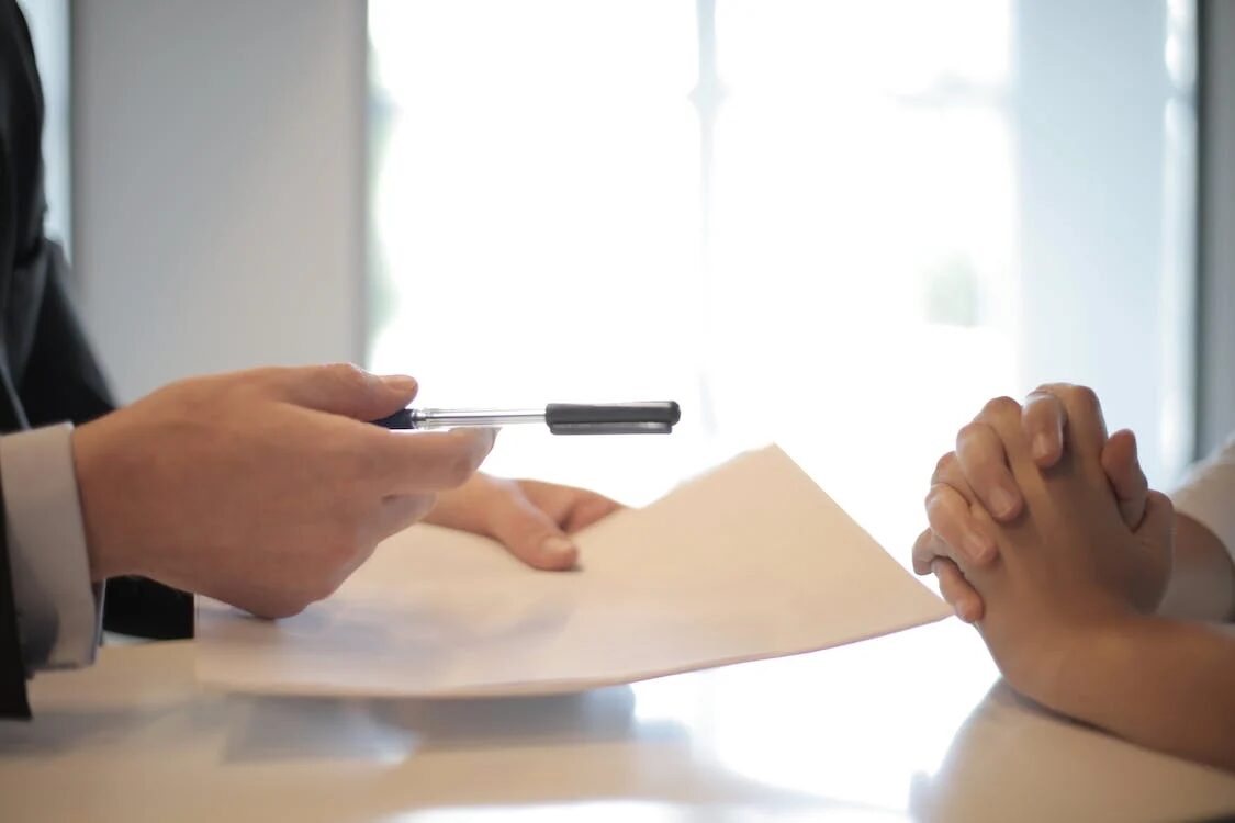 image of a person's hand holding a pen with another person clasping its hand