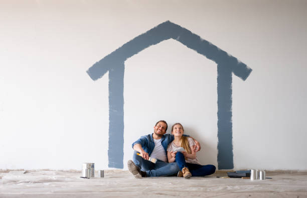 a man and a woman sitting under a house outline they painted on the wall
